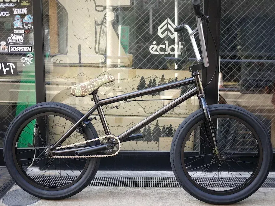A black bmx bike is parked in front of a store.
