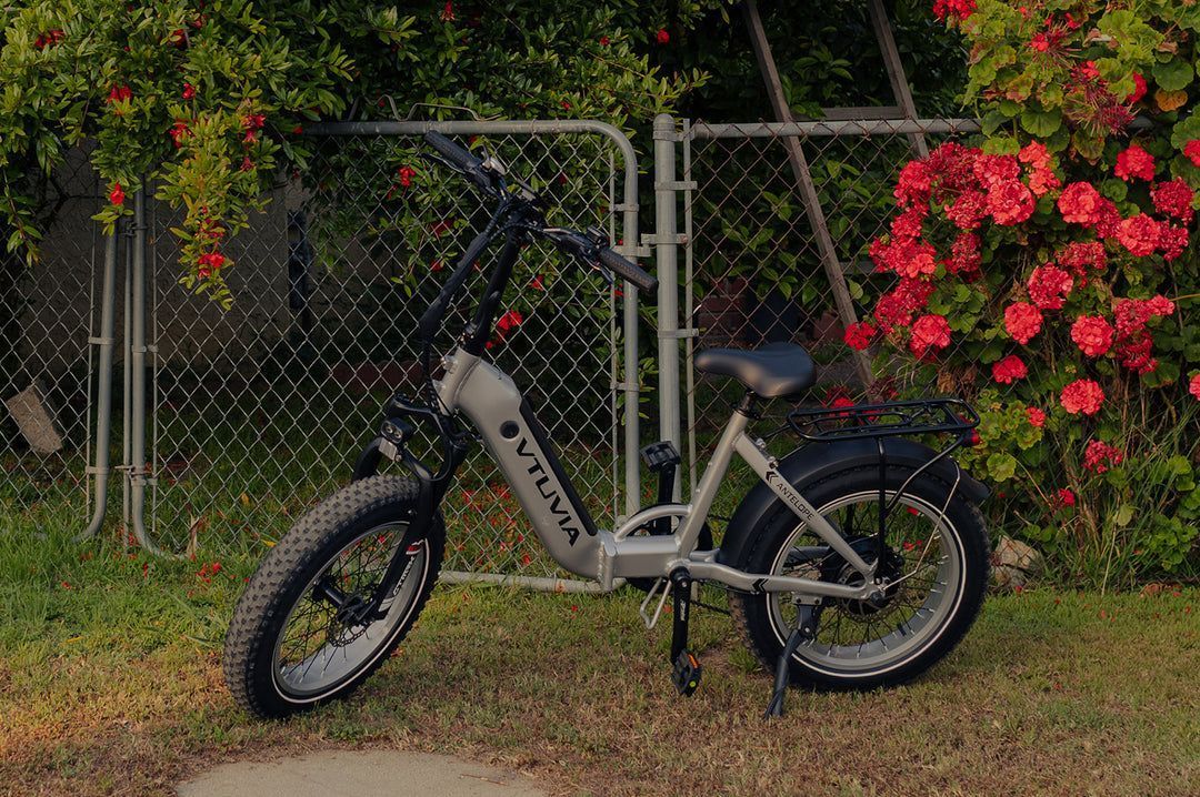 An electric bike is parked in front of a chain link fence.