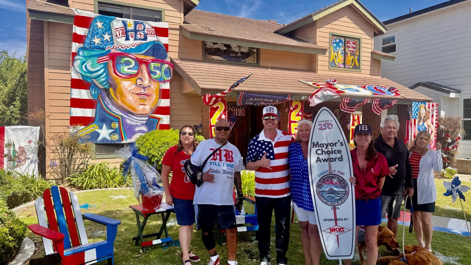 Patriotic group posing in front of a house decorated with an American flag and a colorful mural