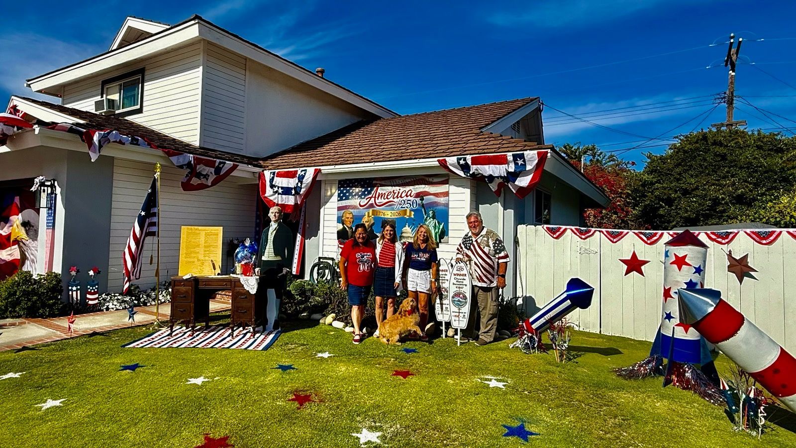 Decorated house with patriotic bunting, stars, and people standing on the lawn during a festive display