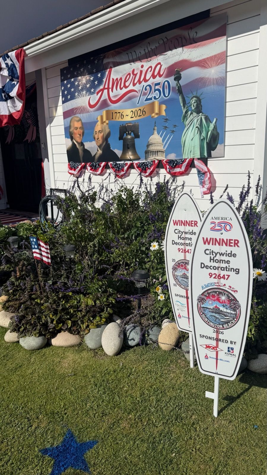 Patriotic yard display with America-themed mural, Statue of Liberty cutout, and trophy sign on the lawn