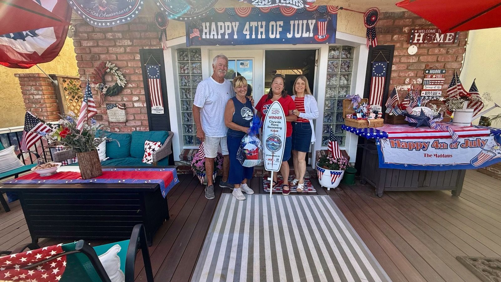 Family posing at a patriotic Fourth of July party booth with red, white, and blue decorations.