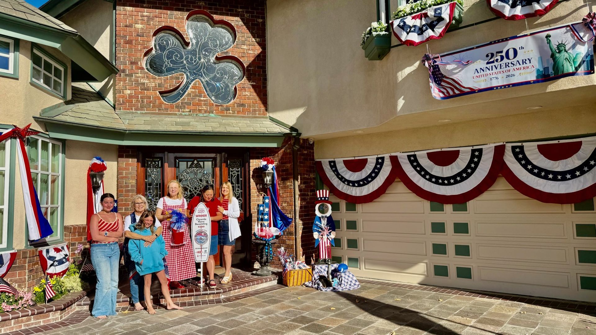Group posing outside a house decorated with red, white, and blue bunting and patriotic banners