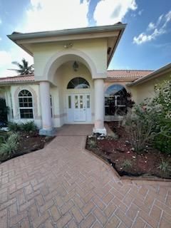 A large white house with a brick walkway leading to the front door.
