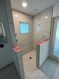 A bathroom with a walk in shower and a window.