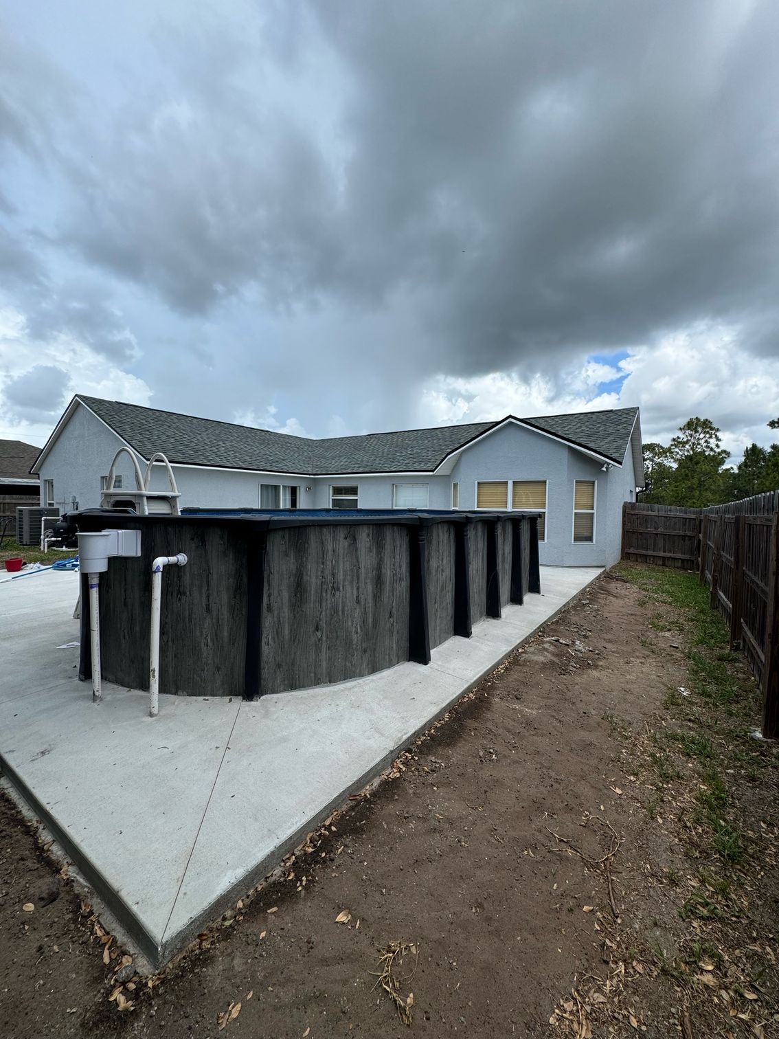 A large swimming pool is sitting in the backyard of a house.
