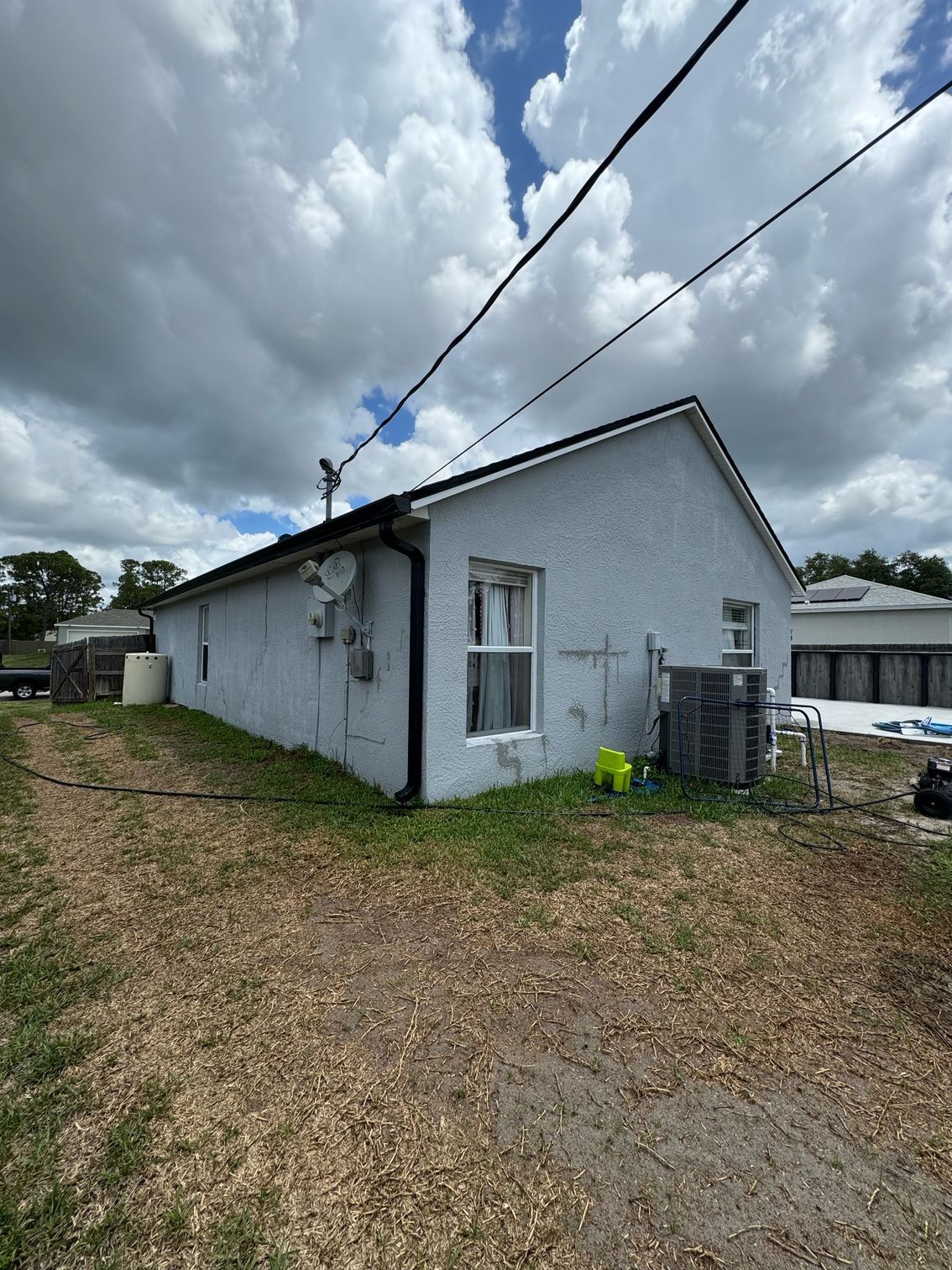 A white house with a lot of windows is sitting on top of a dirt field.