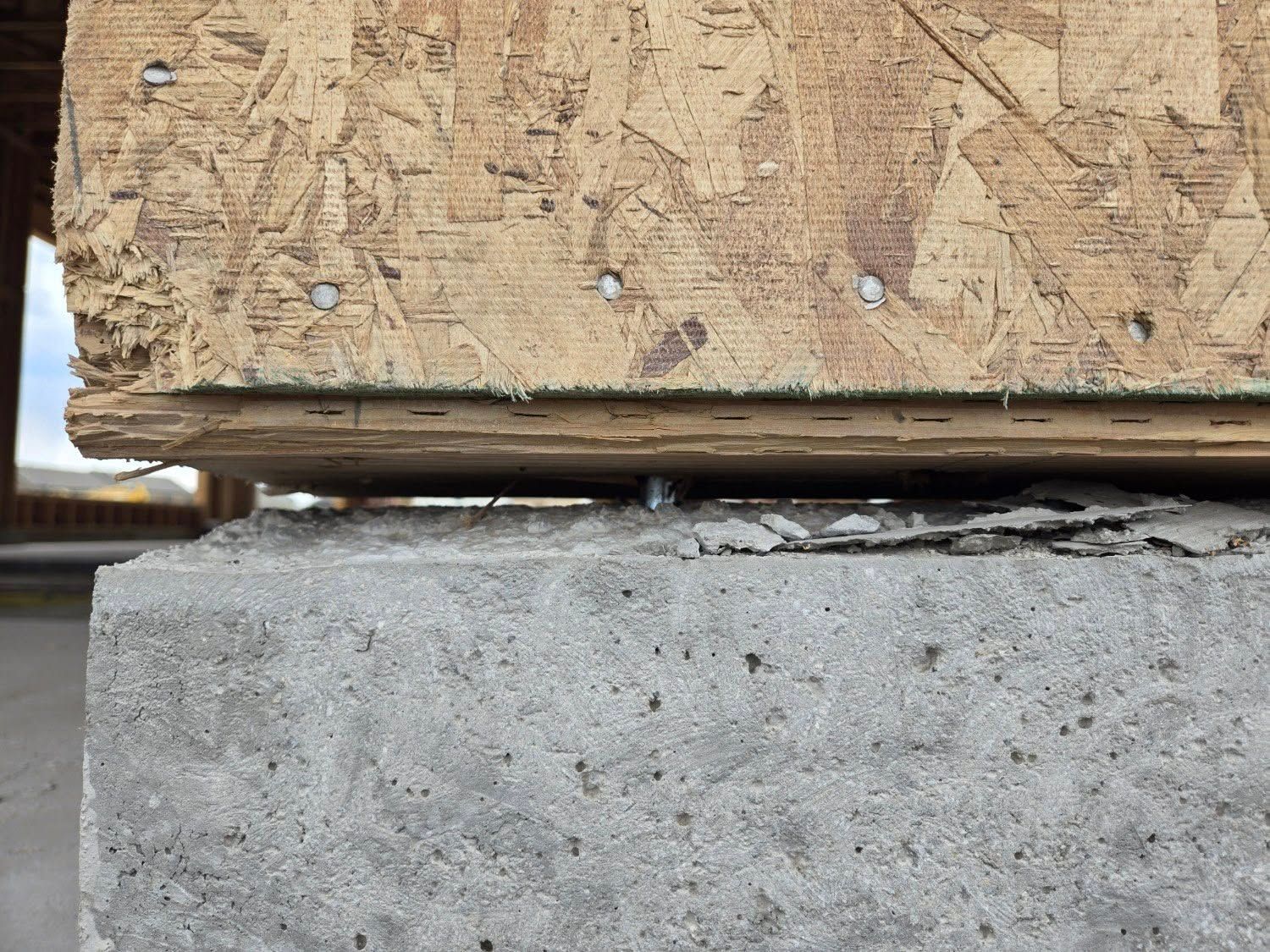 Close-up of weathered wood plank on a concrete block, showing a gap between the two materials.