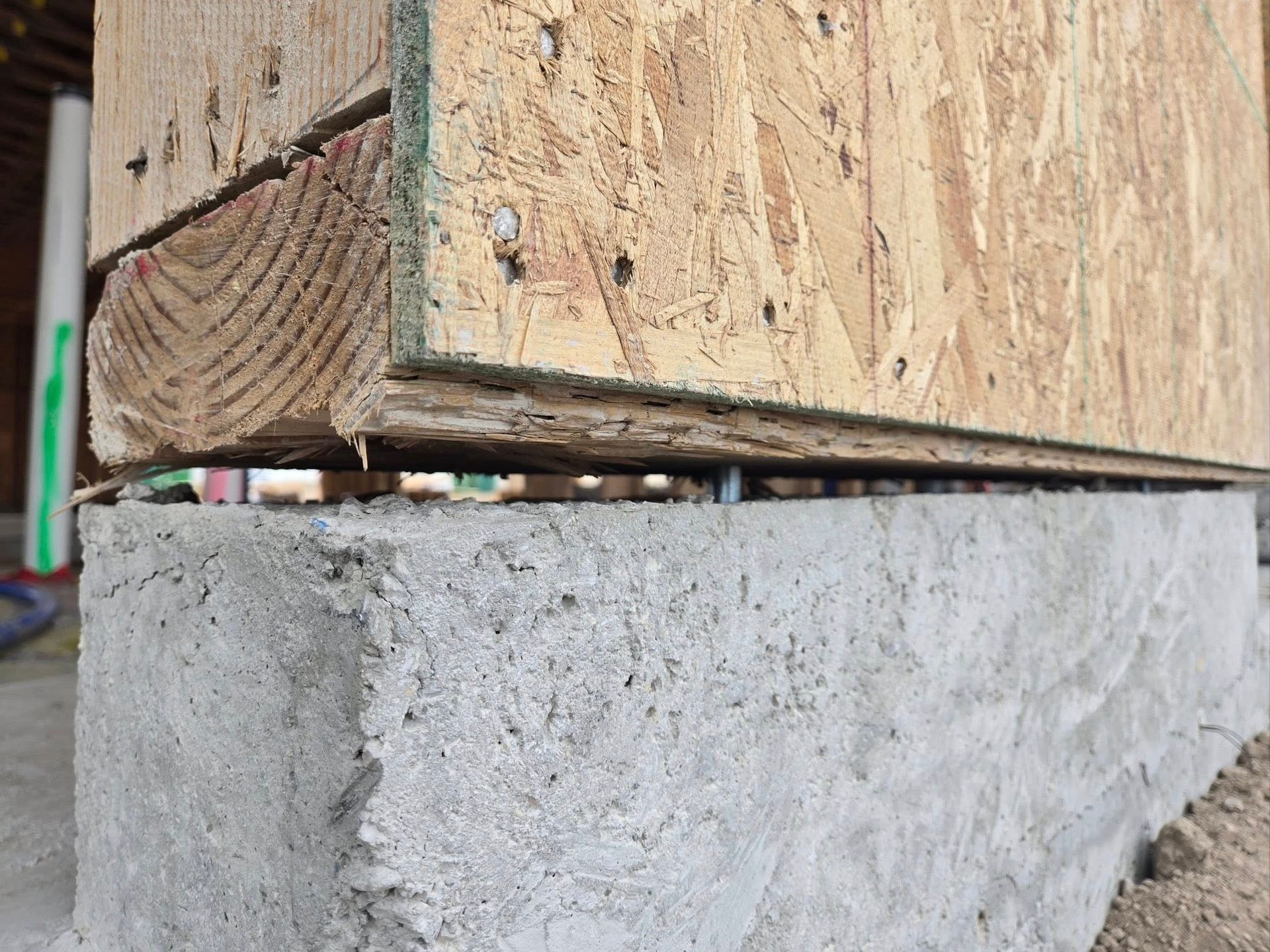 Close-up of a wood-framed structure base sitting on a concrete foundation.