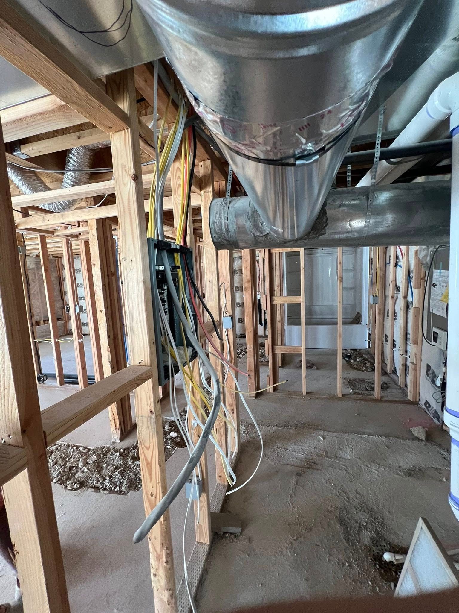 Construction site: exposed wooden framing, ductwork, electrical wiring, and a gray floor.
