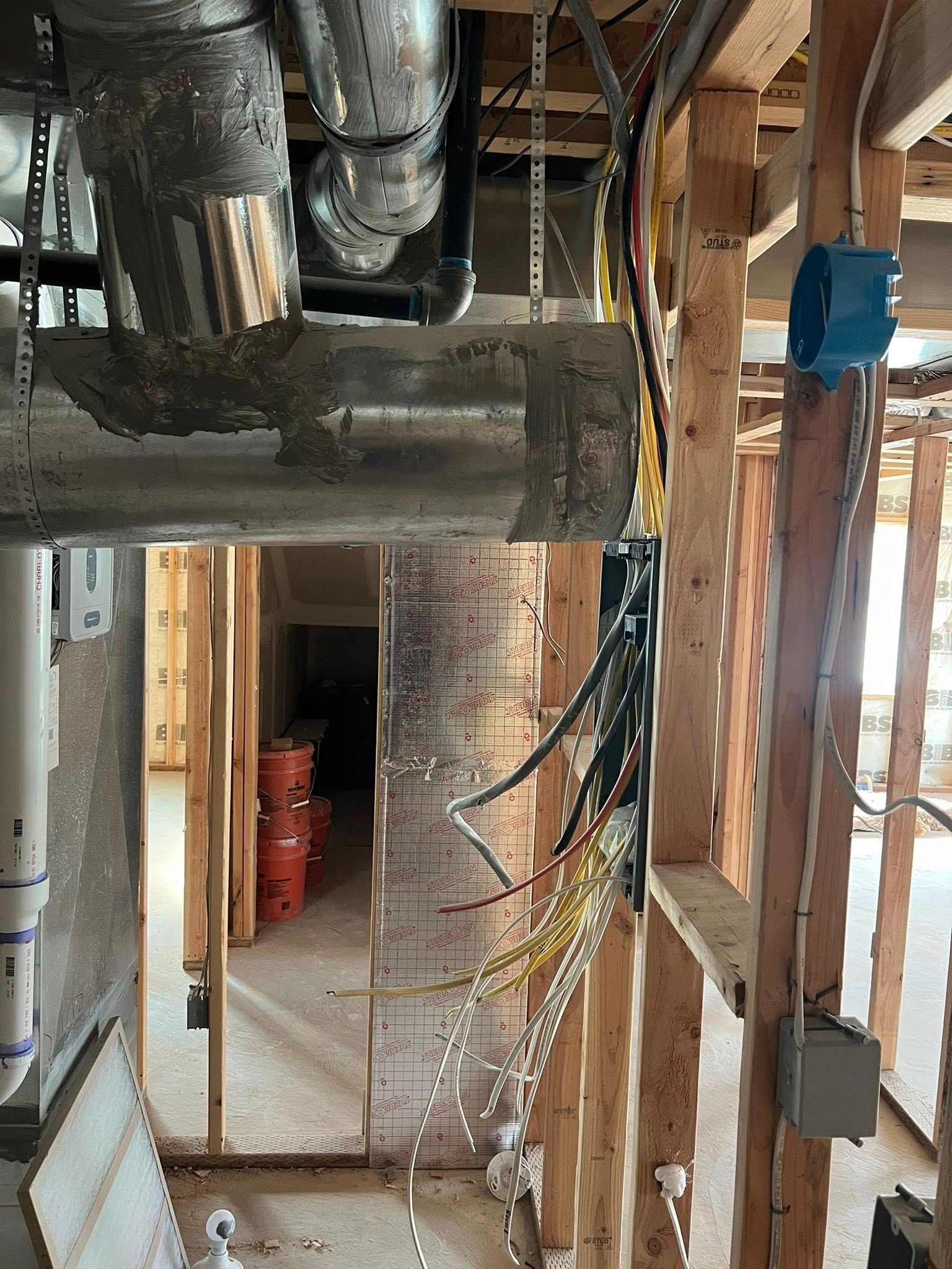 Construction site interior: ductwork, electrical wiring, wooden framing, and blue electrical box.
