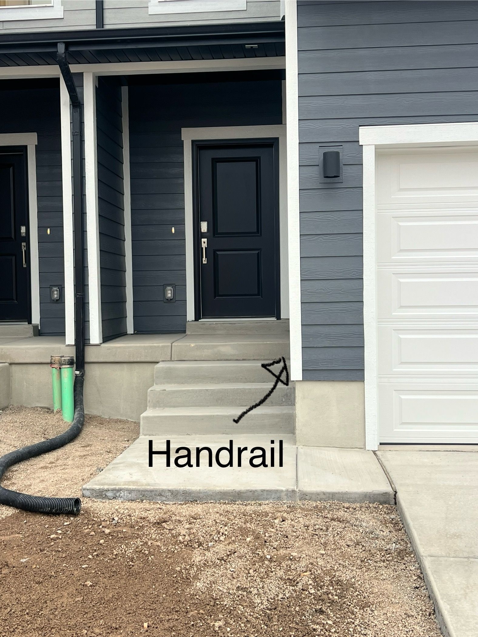 Gray concrete steps leading to a black front door on a dark gray house. No handrail.