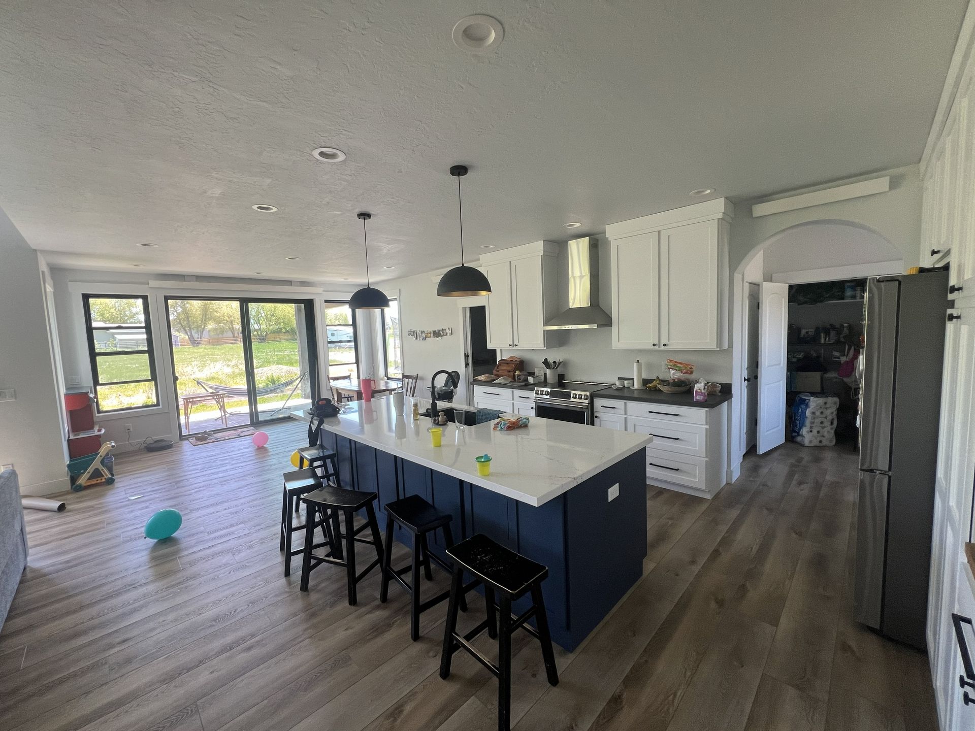 Spacious kitchen with blue island, white cabinets, stainless steel appliances, and large sliding doors.