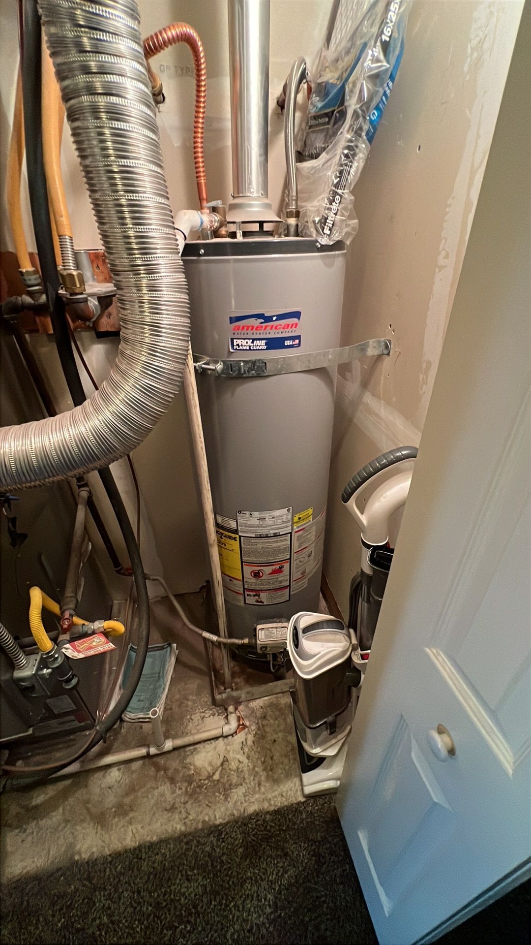 Water heater in a utility closet with a flexible metal vent pipe.