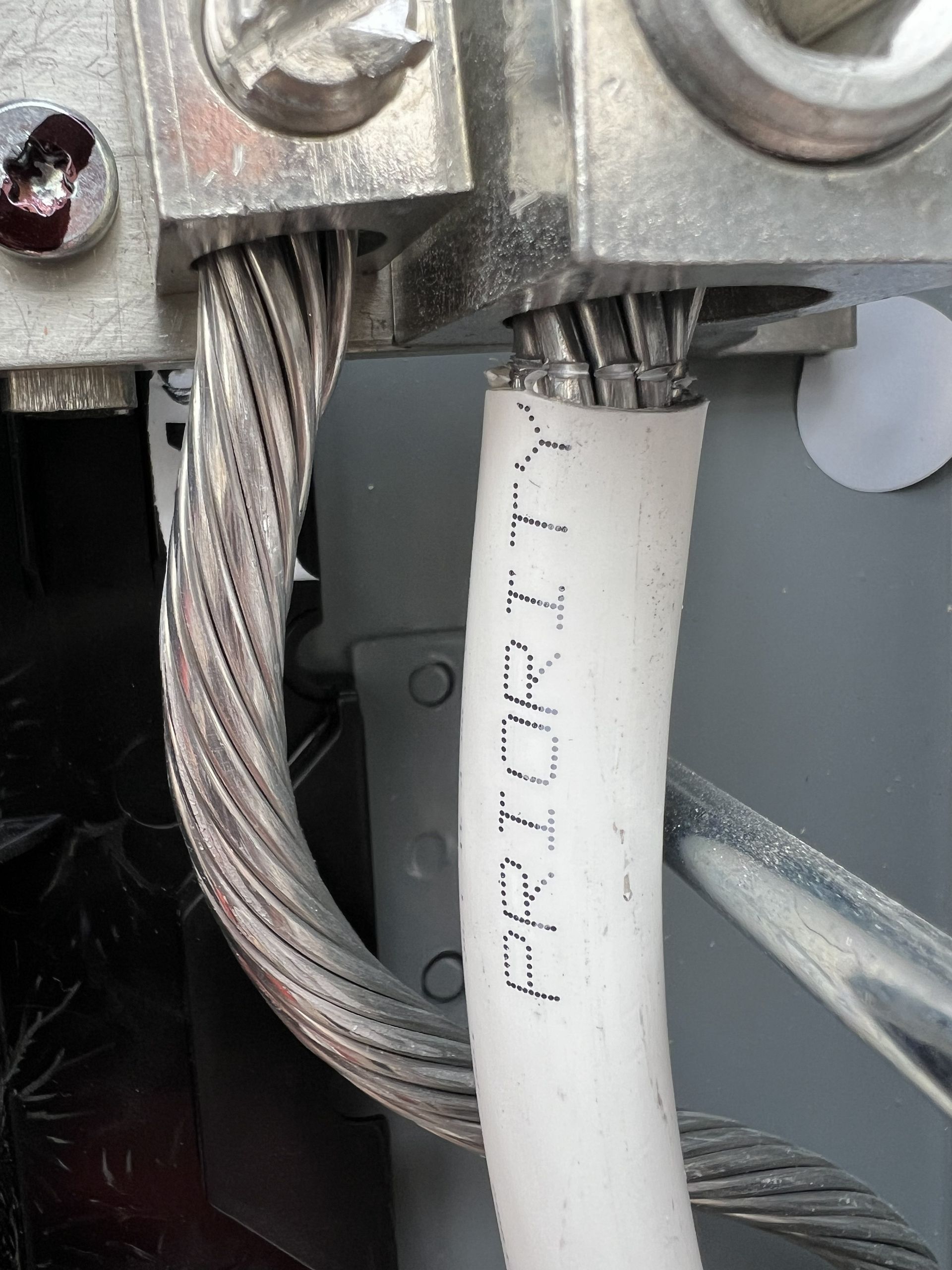 Silver electrical wires connected to a metal terminal block, with 