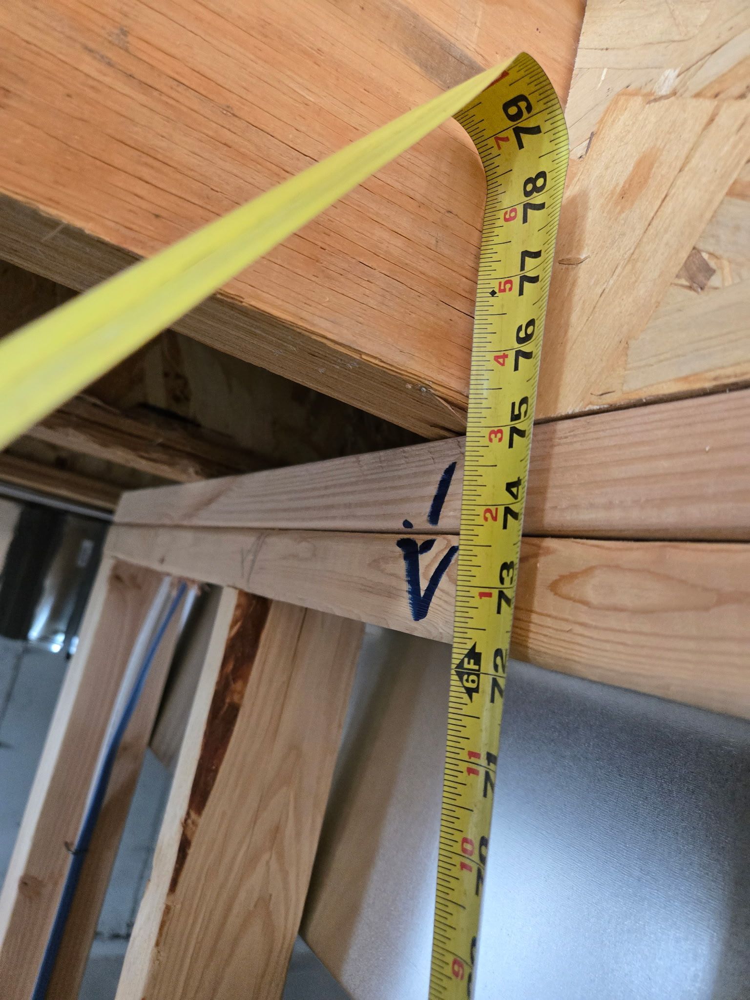 Yellow tape measure shows a measurement of 74 inches in a wooden construction setting.