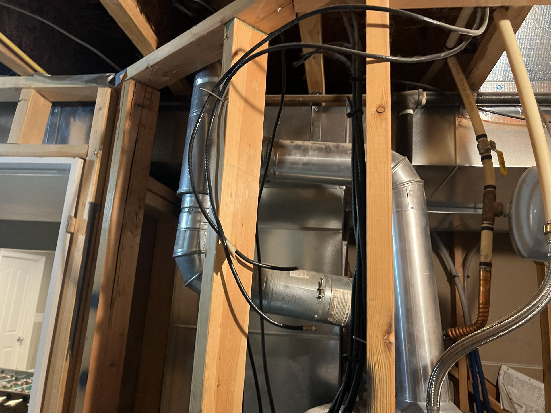 Framed wooden structure with ductwork and pipes running through it.