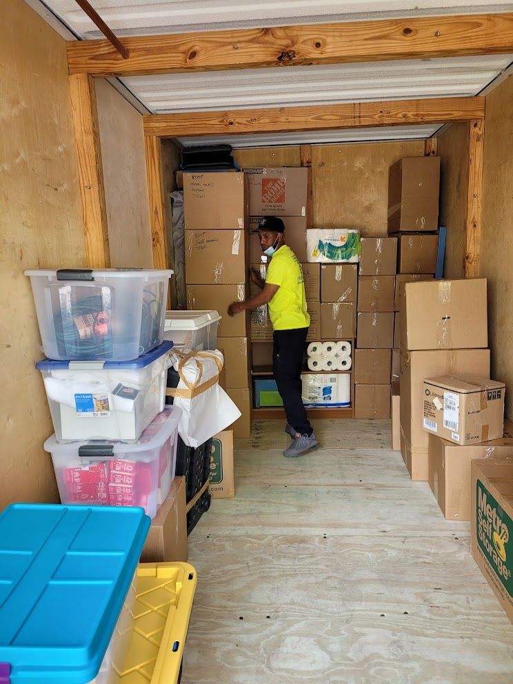 A man in a yellow shirt is standing in a room filled with boxes.