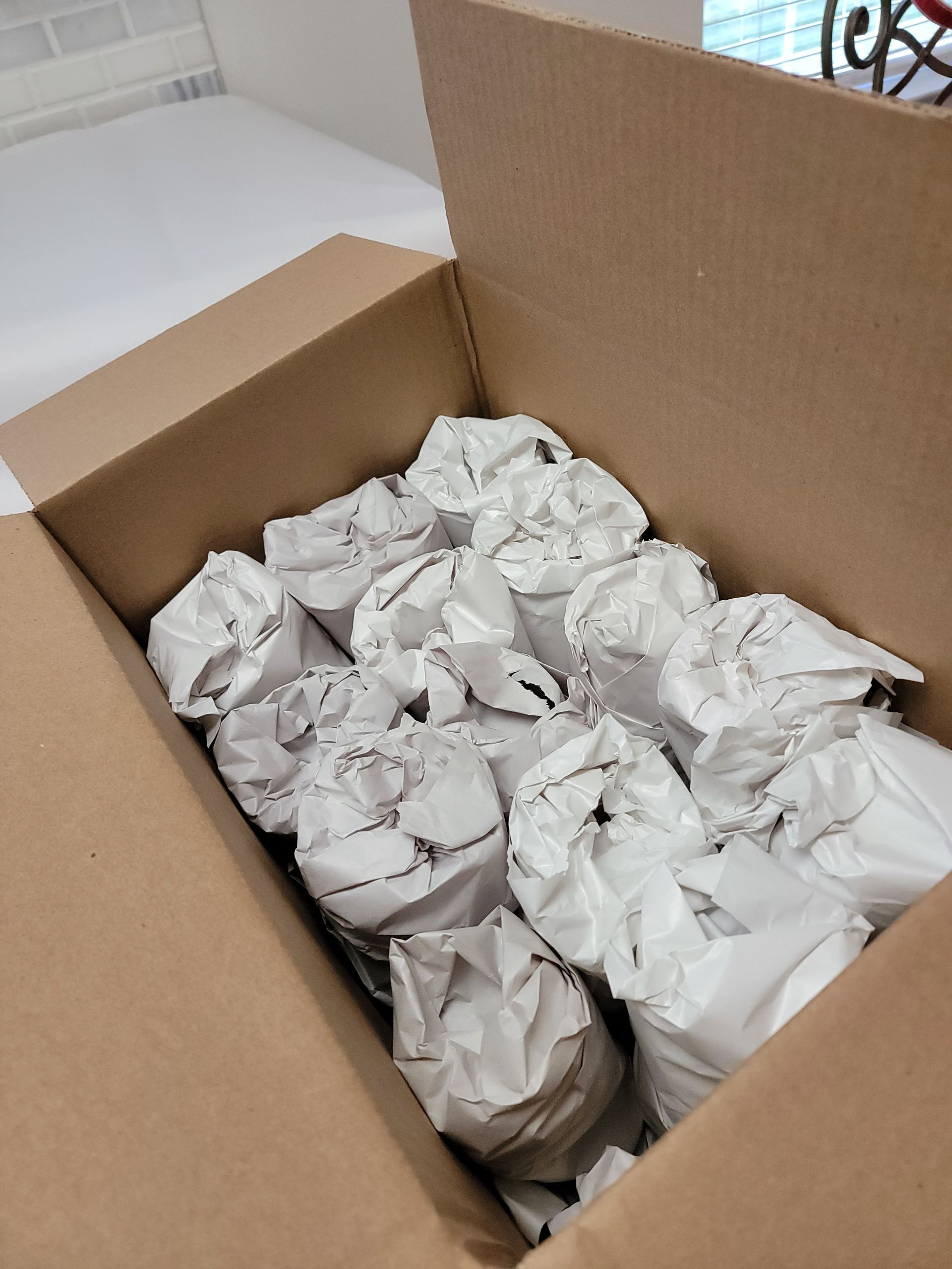 Cardboard box filled with items wrapped in white paper.