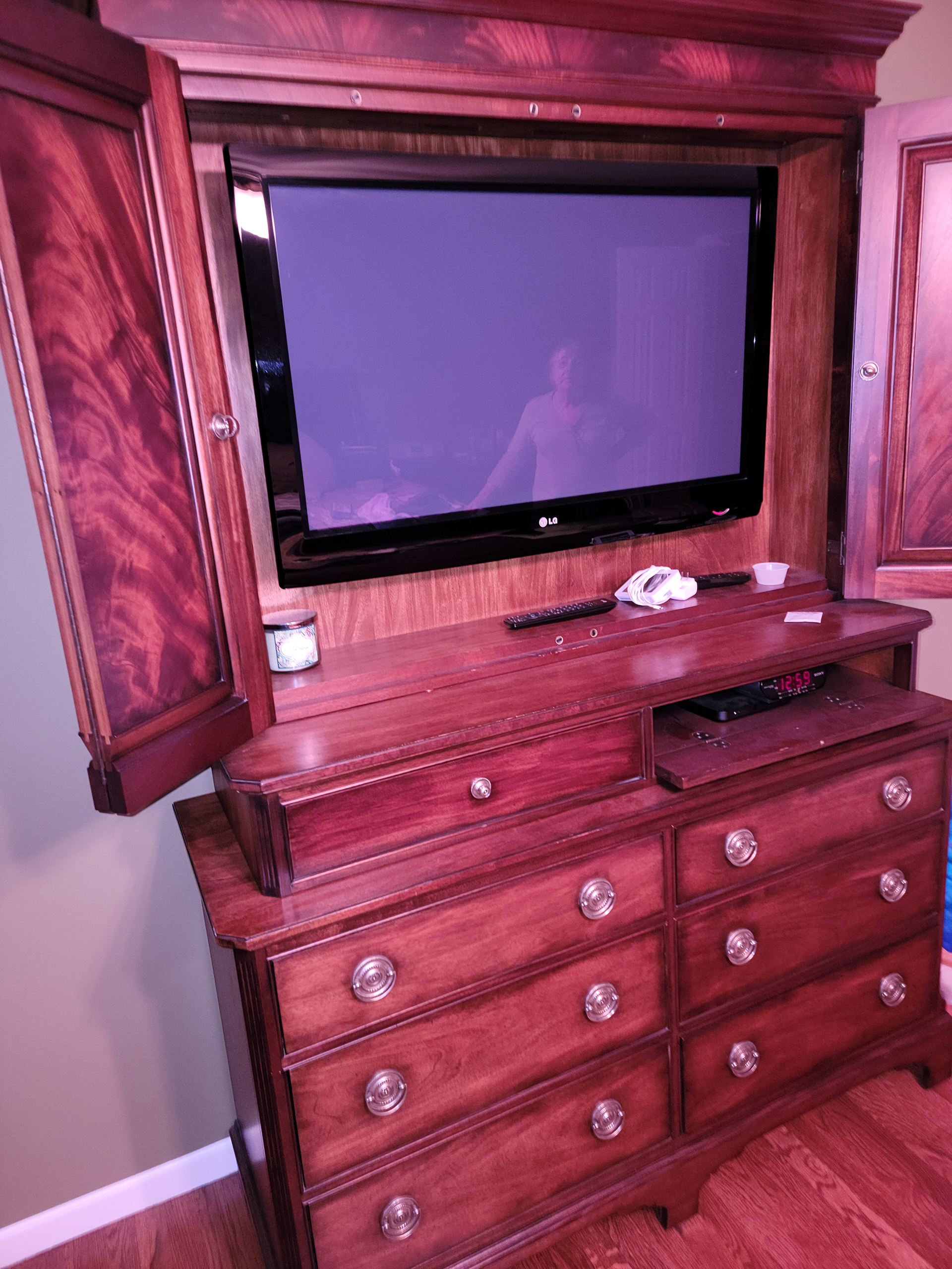 A wooden dresser with a flat screen tv on top of it