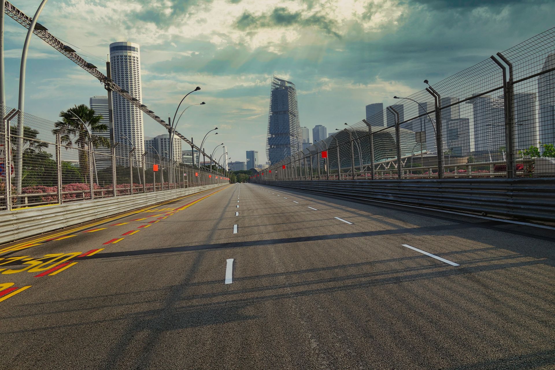 An empty road with a fence and a city in the background.