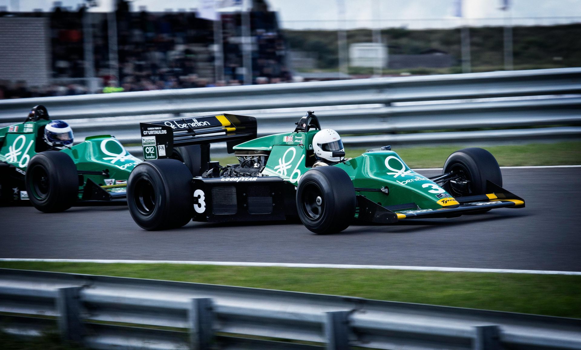 Two green race cars are racing on a race track.