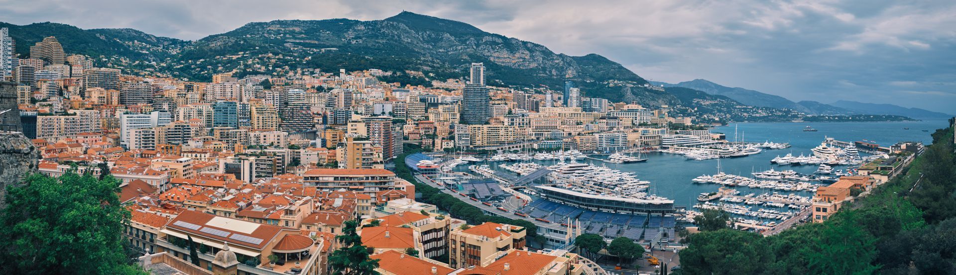 An aerial view of a city with a harbor and mountains in the background.
