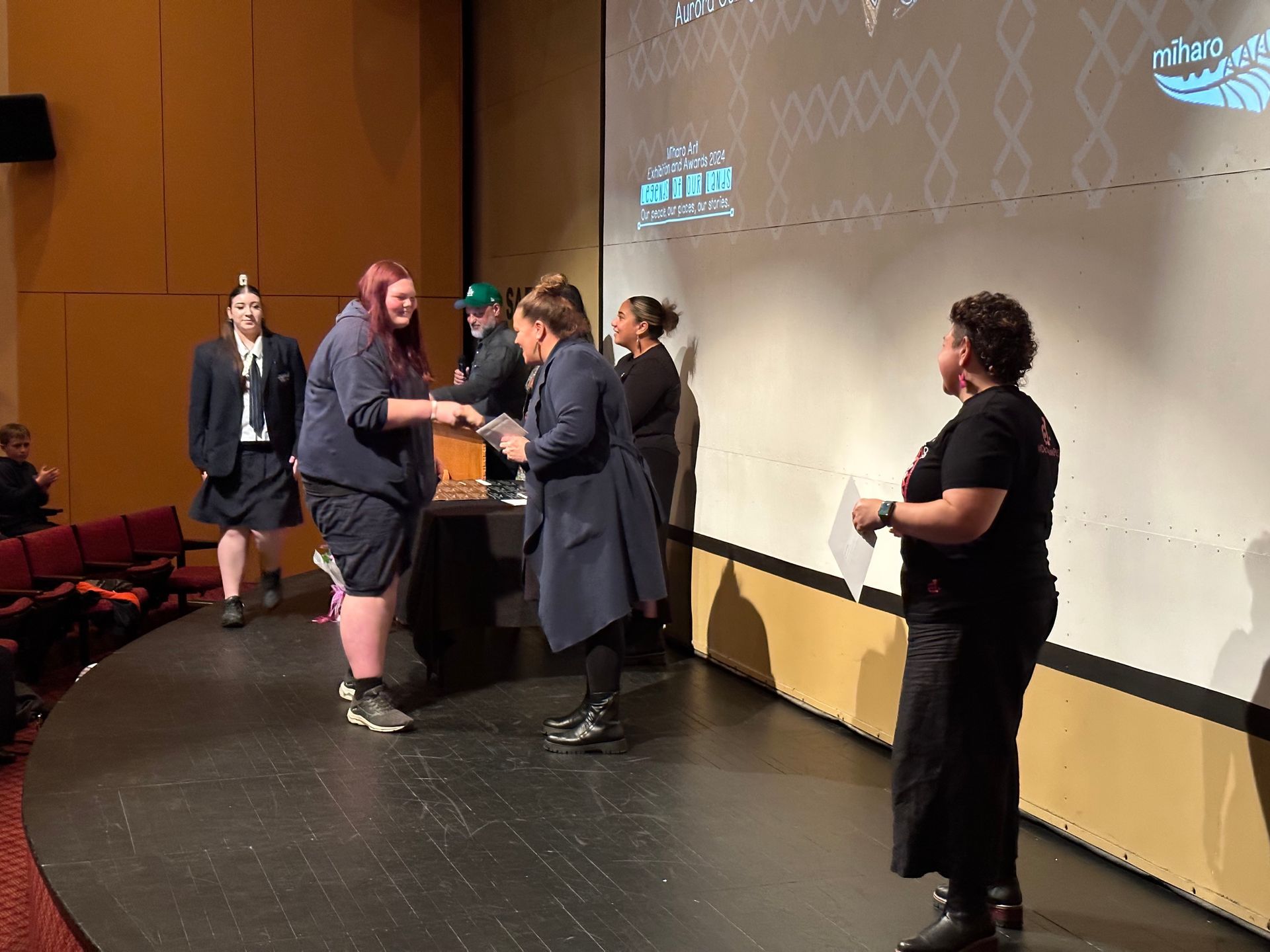 A group of people are standing on a stage shaking hands.