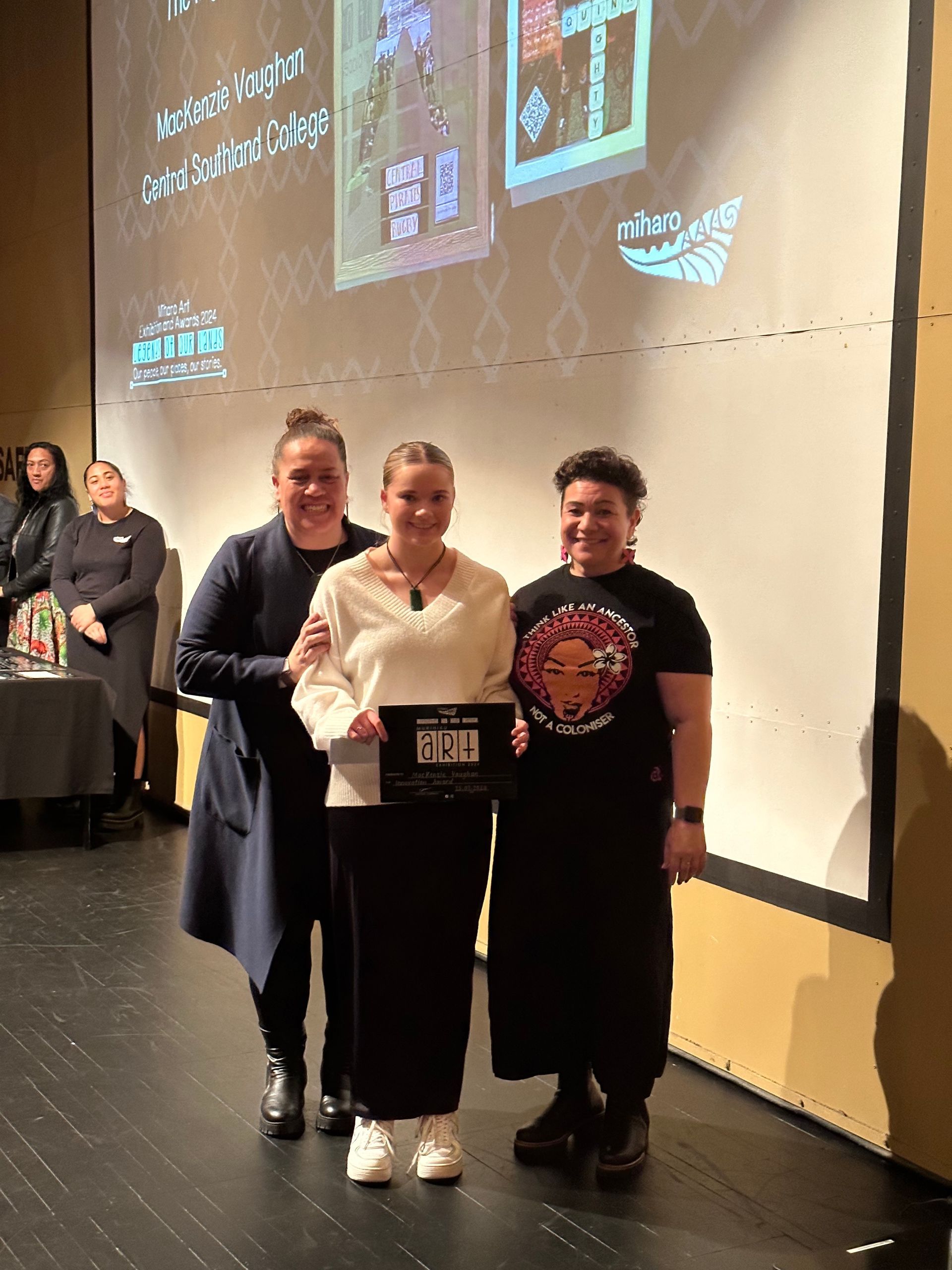 Three women are standing on a stage