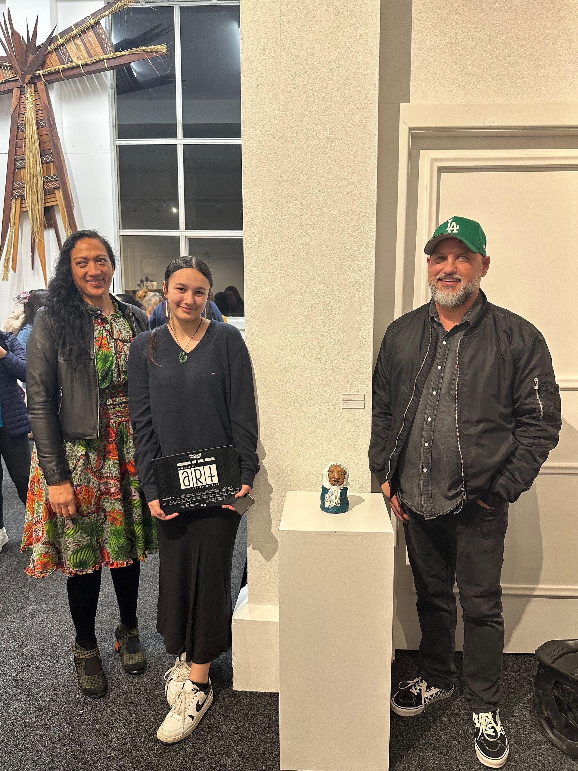A group of people are standing next to an art piece