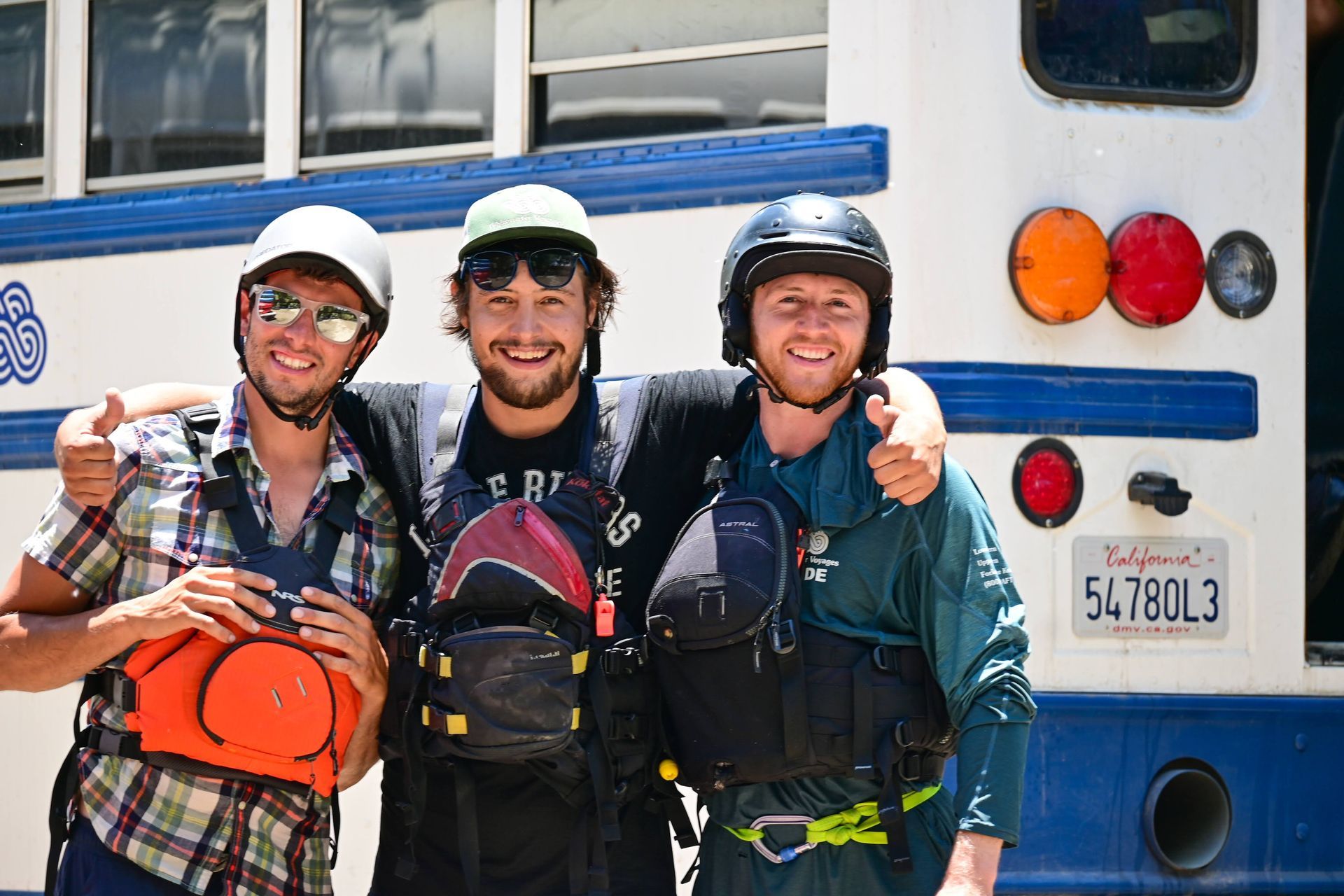 4 river guides smiling in front of a bus