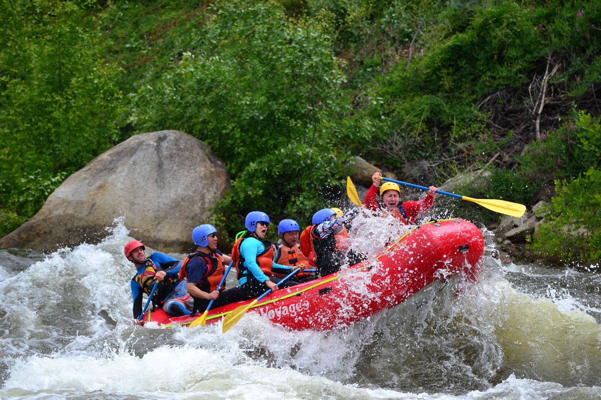 whitewater rafting with red raft going over rapids