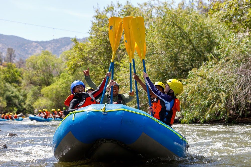 a group of people on a blue raft with their paddles in the air