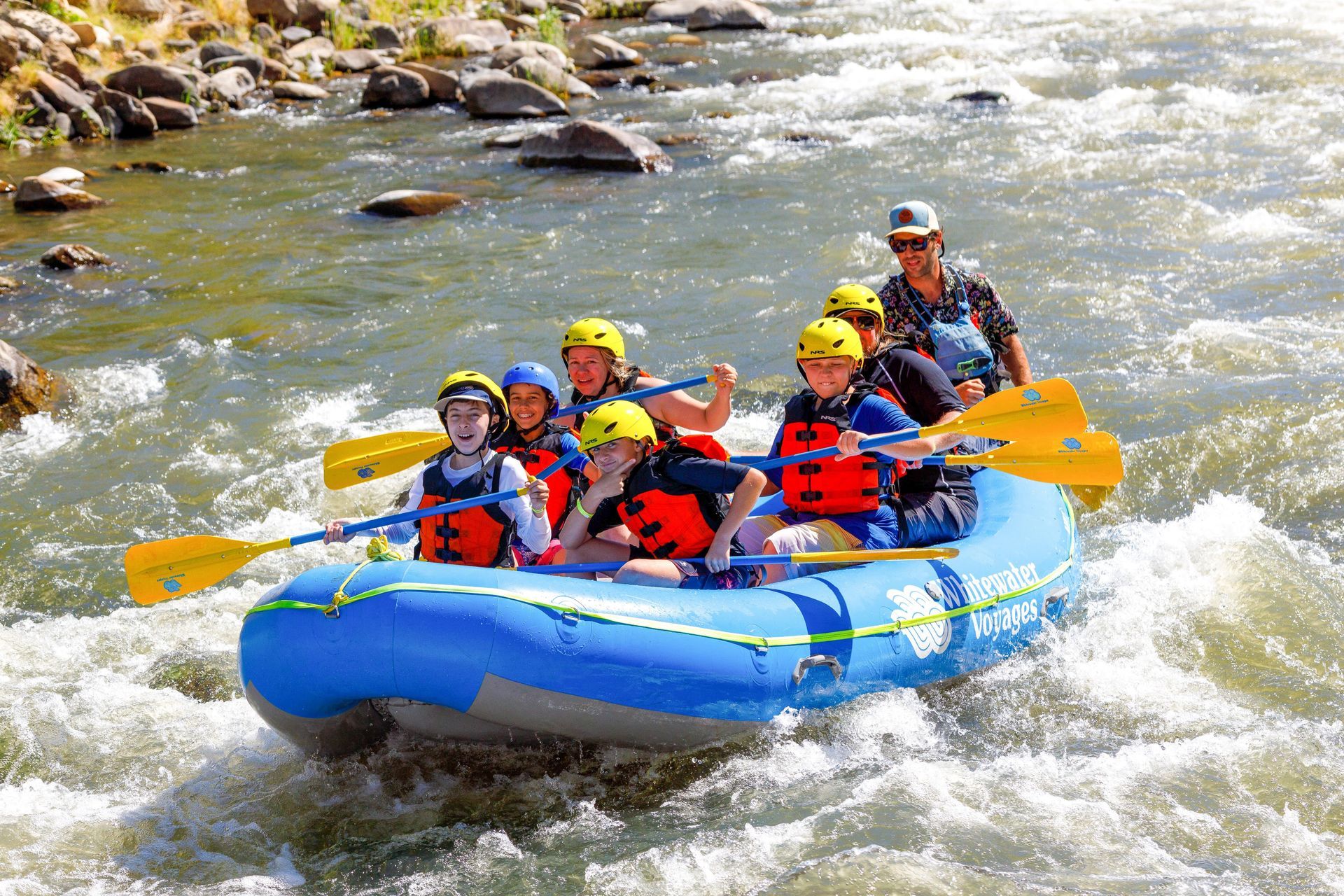 a blue raft with kids going down rapids