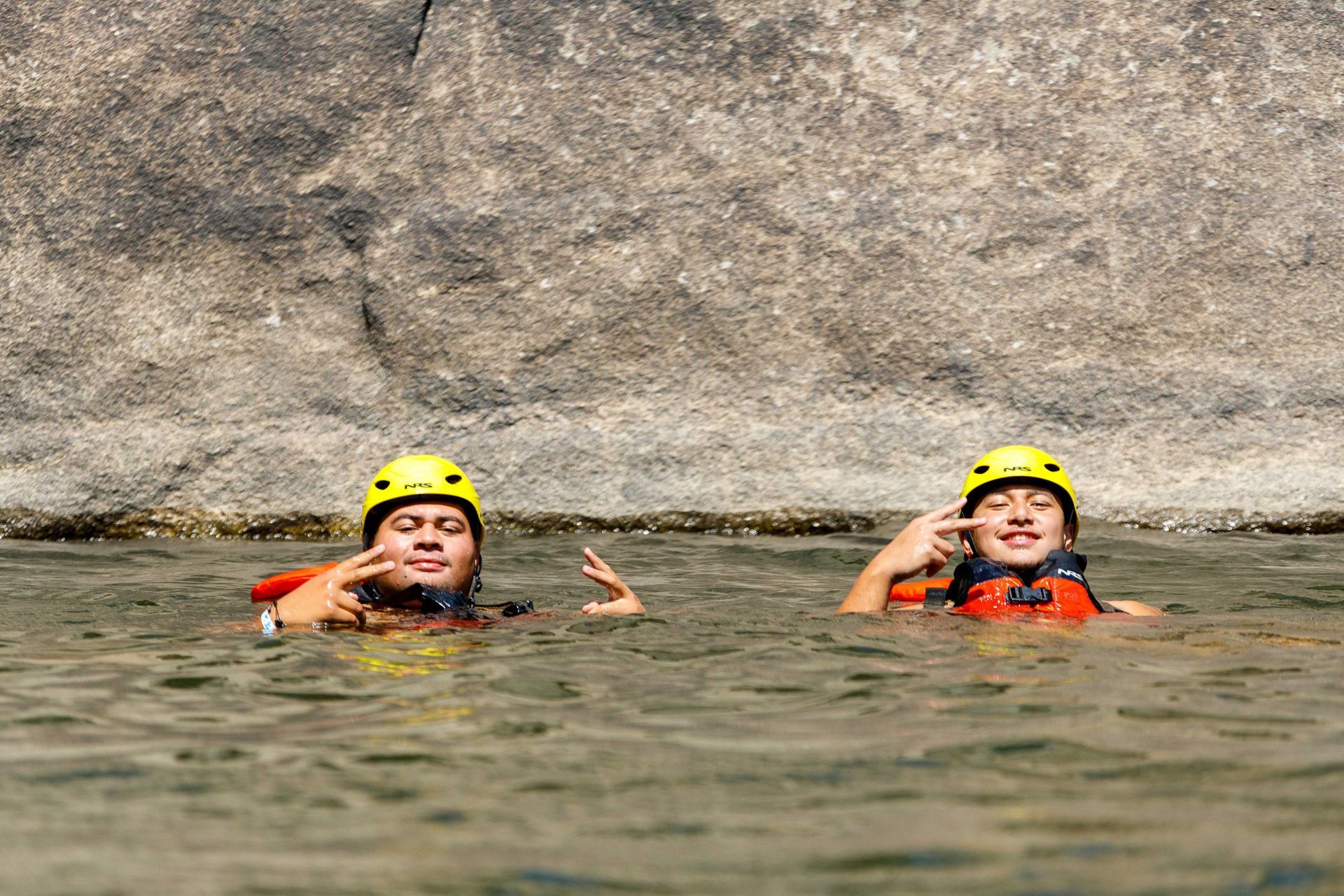 Two people are floating in the water talking on their cell phones.