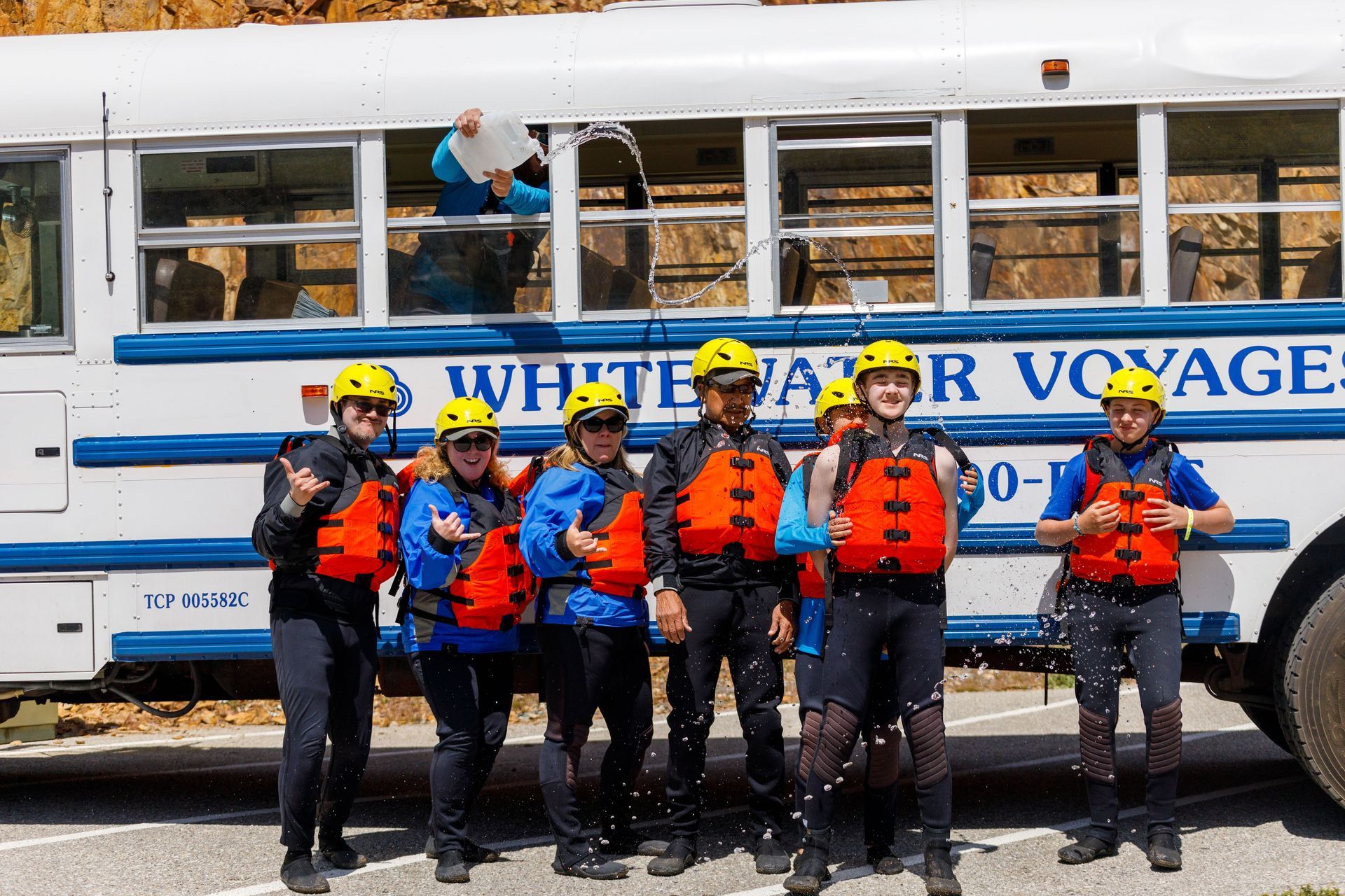 a group of people standing in front of a bus about to go whitewater rafting