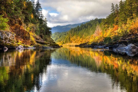 a river with fall colors of trees in the background