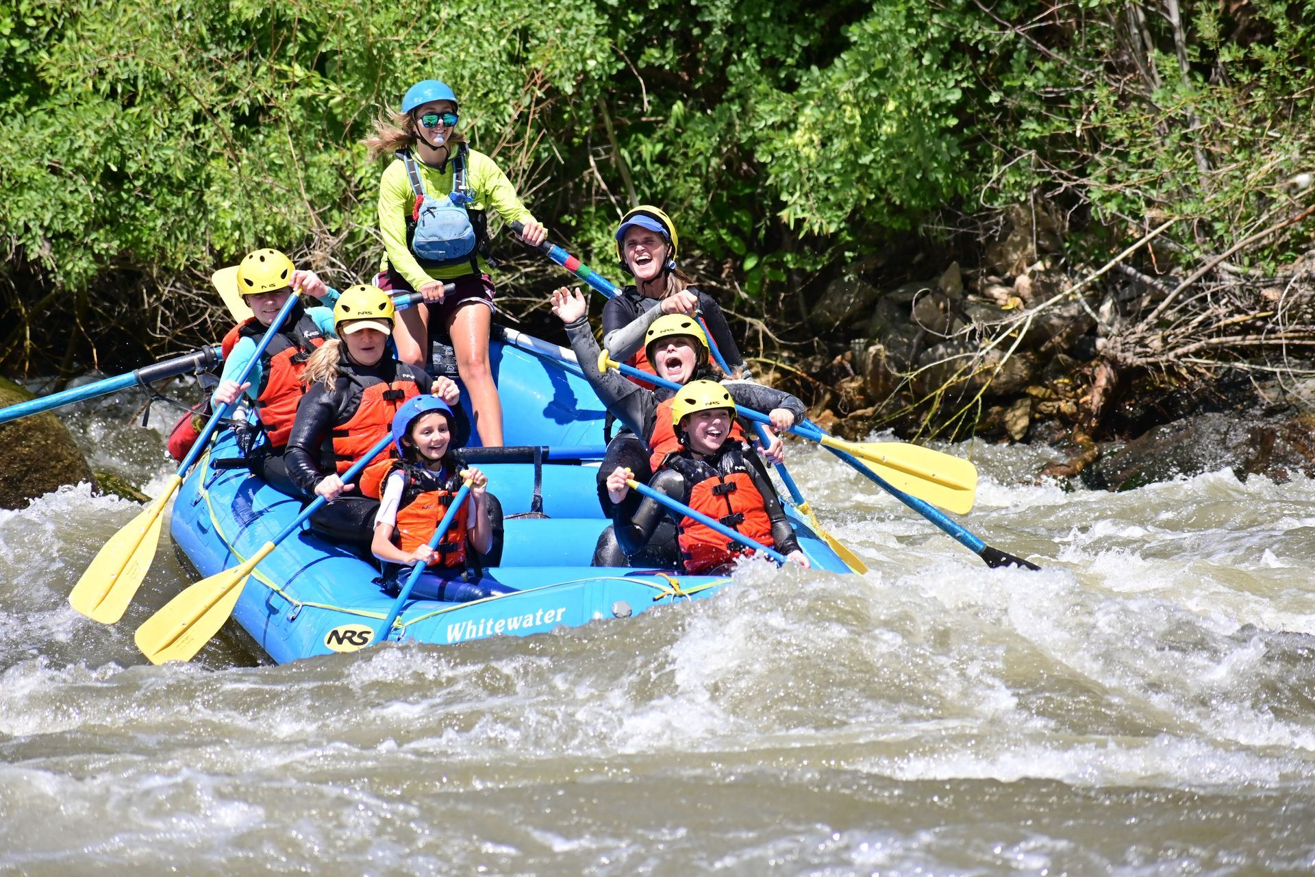 a blue raft going through whitewater rapids