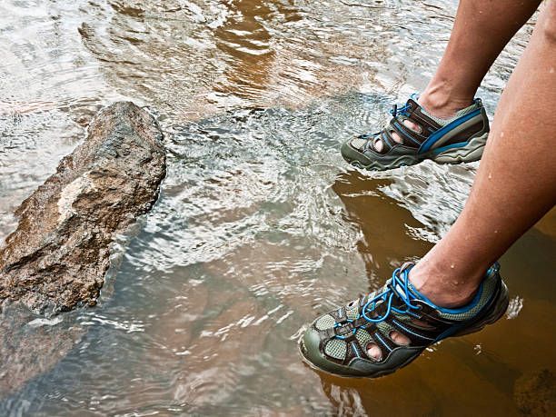 Two feet with water shoes dangle in a river