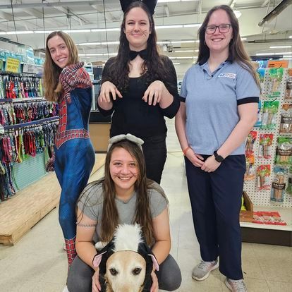 A group of women are posing for a picture with a dog in a pet store.