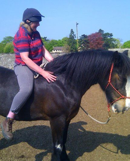Lorraine sitting on Dolly the horse bareback with just a headcollar and single rope.