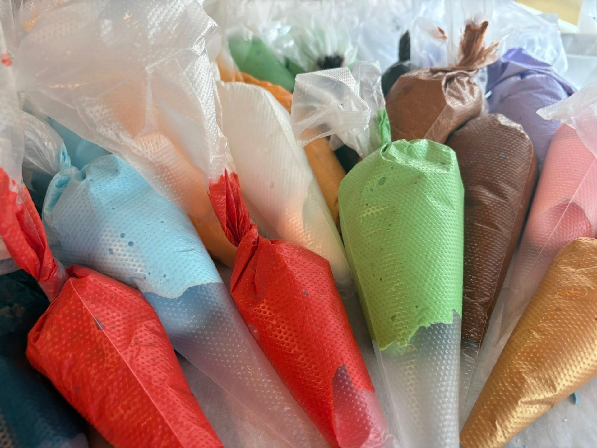 Colorful icing in disposable piping bags ready for decorating.