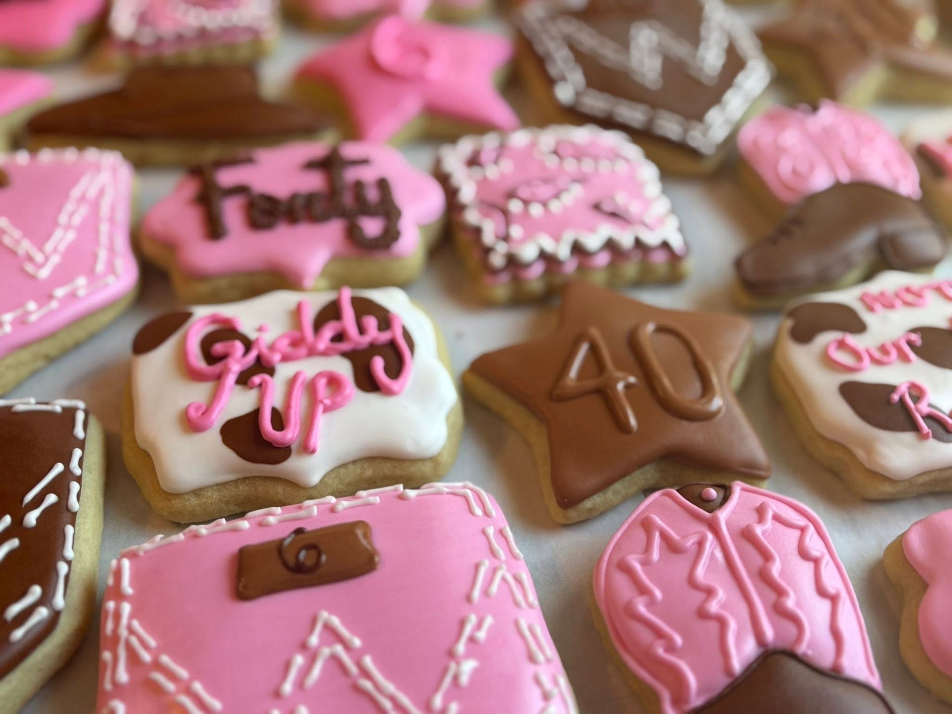 Cookies decorated with pink and brown frosting, including the words "Forty" and "Giddy Up".