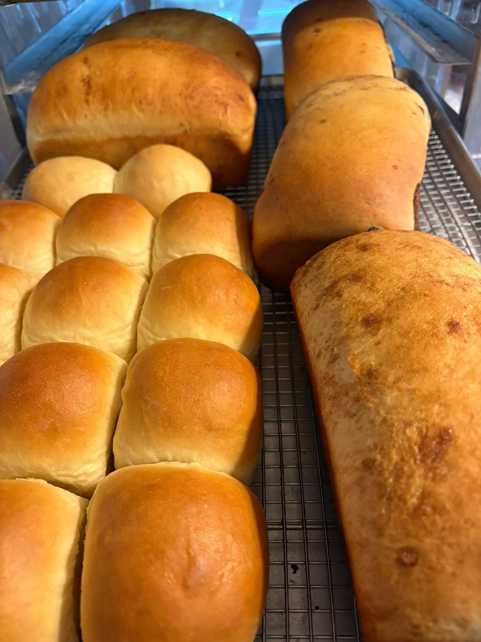Freshly baked bread and rolls on a cooling rack.