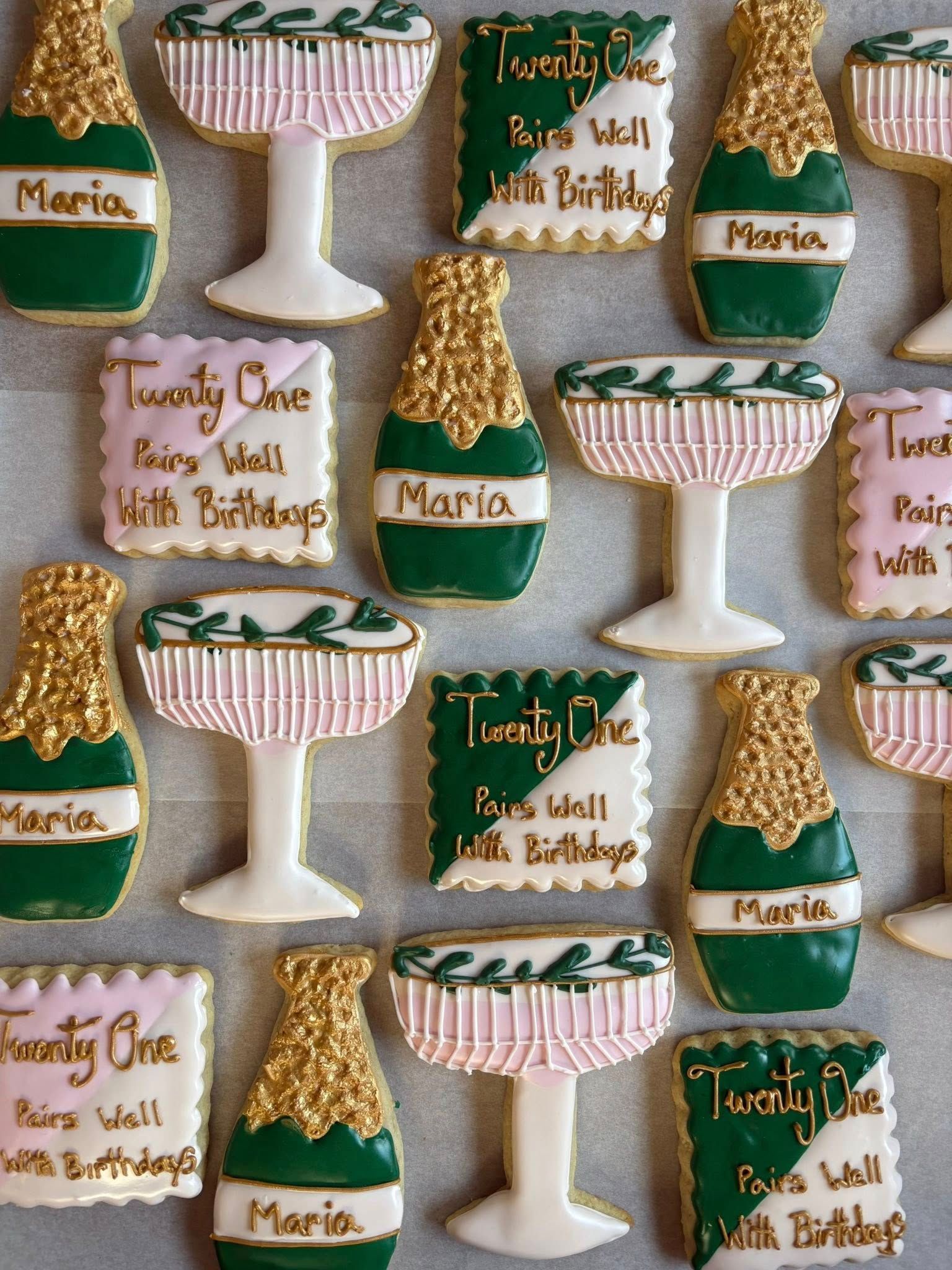 Cookies decorated as champagne bottles, glasses, and square treats, in green, gold, and pink colors.
