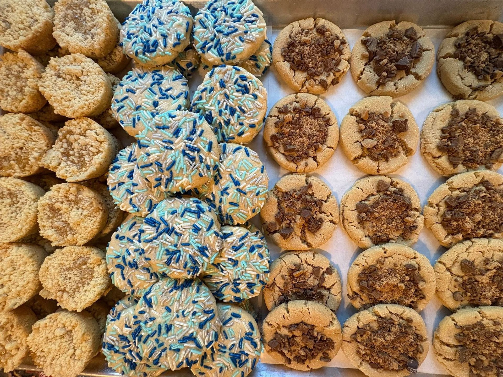 Cookies on a tray: three rows, varieties include sprinkles and crumble topping.