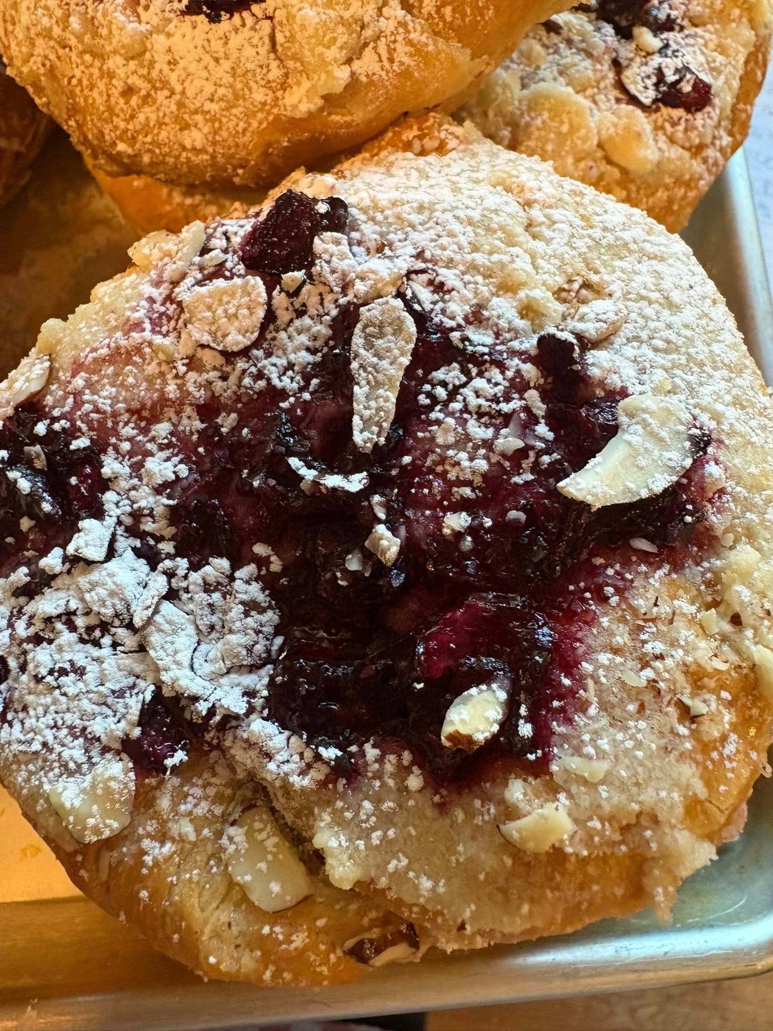 Pastry with berry filling, almond slices, and powdered sugar.