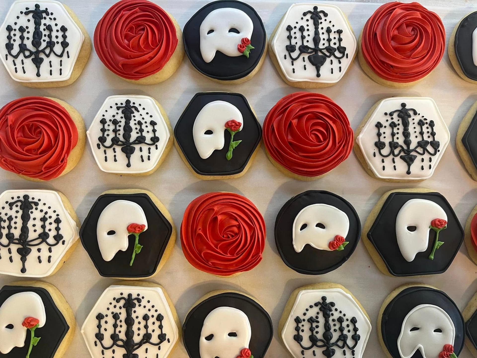 Cookies decorated with red roses, Phantom of the Opera masks, and black and white chandelier designs.