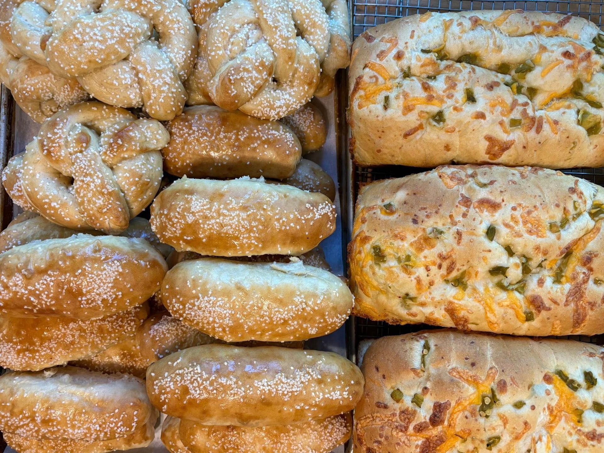 Assortment of baked goods, including pretzels and loaves with cheese and jalapeños.