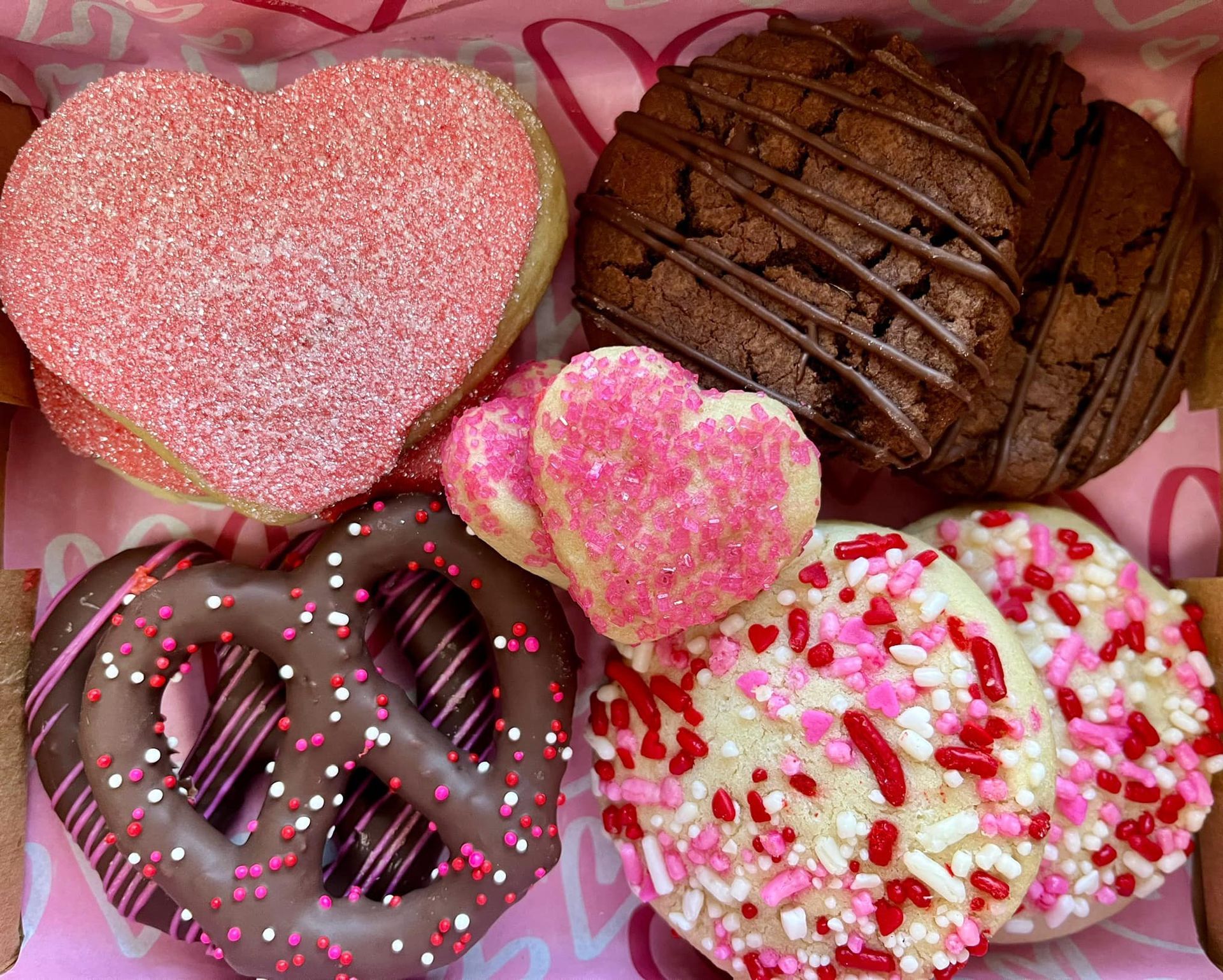 Valentine's Day cookies in a box: heart-shaped, chocolate-covered pretzel, and sprinkles.